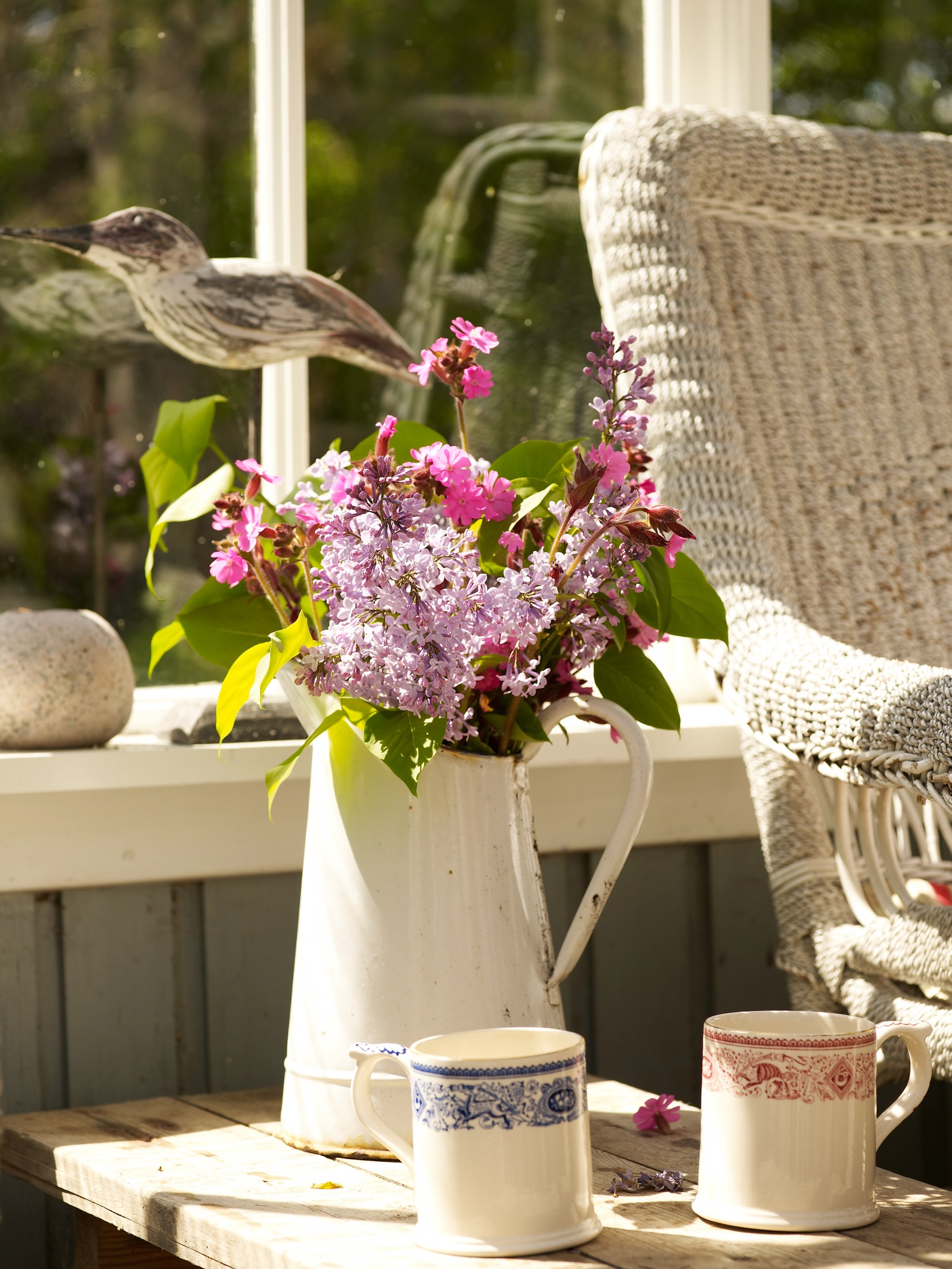 Flower arrangement in rustic jug on conservatory side table